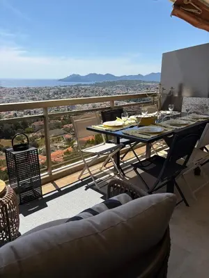 a table and chairs on a balcony with a view at Stunning 3-Room with Panoramic Views Over Cannes in Le Cannet