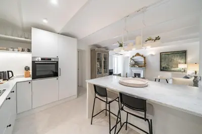 a kitchen with white cabinets and a large island with bar stools at Charme et confort à Cannes près de la Croisette in Cannes