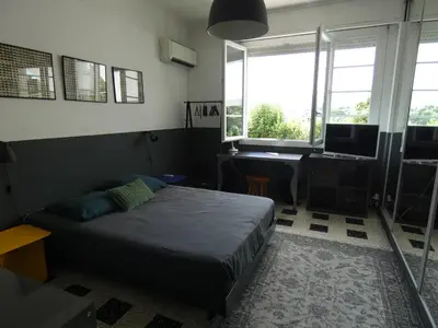 a bedroom with a bed and a desk and windows at Cannes - LE DOLCE appartement de charme - 3 chambres - piscine in Cannes