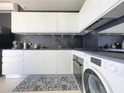 a kitchen with white cabinets and a washing machine at Le KamS in Cannes