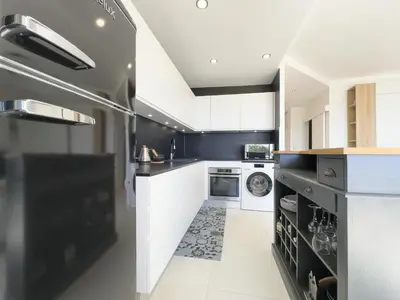 a kitchen with white cabinets and a washer and dryer at Le KamS in Cannes