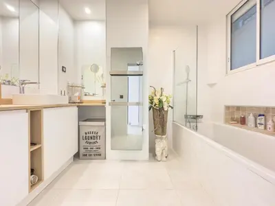a white bathroom with a vase with flowers in it at Le KamS in Cannes
