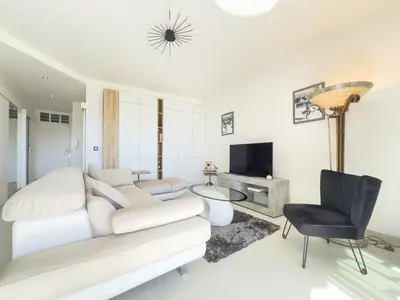 a white living room with a couch and a tv at Le KamS in Cannes