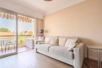 a living room with a couch and a large window at Cannes 2 pièces lumineux terrasse ensoleillée in Cannes