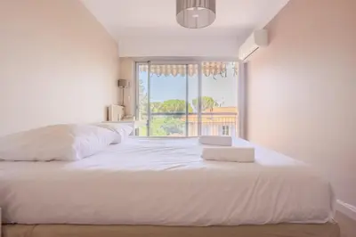 a bedroom with a large white bed with a window at Cannes 2 pièces lumineux terrasse ensoleillée in Cannes