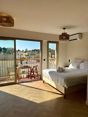 a bedroom with a bed and a balcony with a table at Studio lumineux 5 minutes Croisette et rue Antibes in Cannes