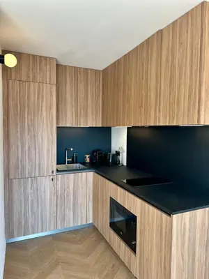 a kitchen with wooden cabinets and a black counter top at Studio lumineux 5 minutes Croisette et rue Antibes in Cannes