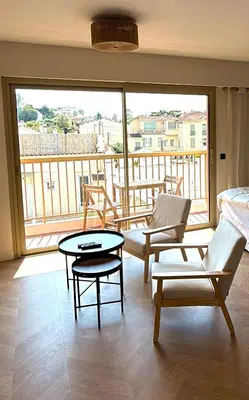 a living room with a table and chairs and a balcony at Studio lumineux 5 minutes Croisette et rue Antibes in Cannes