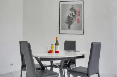 a dining room table with chairs and a bottle of wine at Charmant 2 pièces MEYNADIER-FORVILLE A1B269 in Cannes