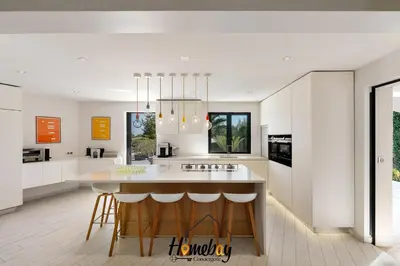 a kitchen with white cabinets and a island with bar stools at Villa Rose Pool Sea View Super Cannes in Vallauris