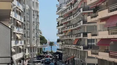 a city street with tall apartment buildings and the ocean at 2 pieces 50 metres des plages in Cannes