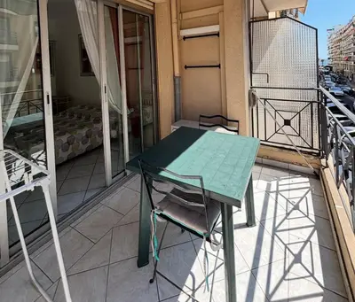 a green table and chair on a balcony at 2 pieces 50 metres des plages in Cannes