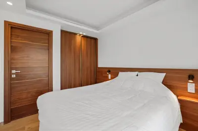 a bedroom with a white bed and wooden doors at REF 2006 - Cannes Croisette - Luxurious apartment with sea view for rent in Cannes