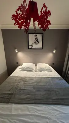 a bedroom with a large bed with red chandeliers at Renovated & cozy apartment in Cannes