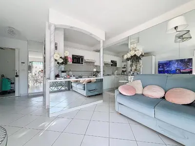 a living room with a blue couch and a kitchen at INTUITION Studio avec terrasse 3min Croisette in Cannes