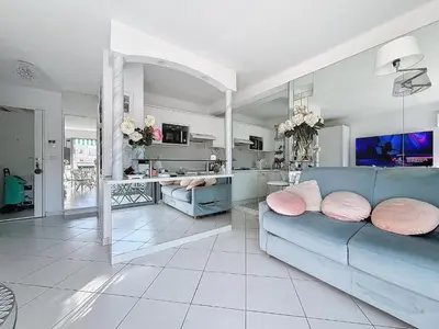 a living room with a blue couch and a kitchen at INTUITION Studio avec terrasse 3min Croisette in Cannes
