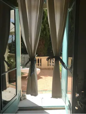 an open window with curtains looking out onto a patio at 170 m2 with terrace near Croisette in Cannes