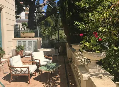 a patio with chairs and a table and flowers at 170 m2 with terrace near Croisette in Cannes