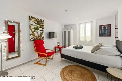 a bedroom with a bed and a red chair at Studio plage et palais Cannes meynadier 1 in Cannes