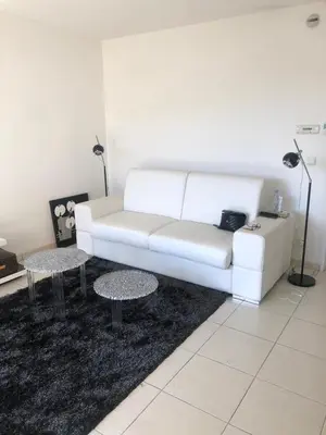 a living room with a white couch and two tables at Centre Cannes Bristol in Cannes