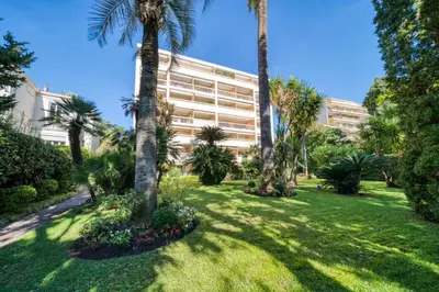 a park with palm trees and a building at REF 1413 - Cannes Center Appartment for rent in Cannes