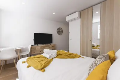 a bedroom with a bed with a television and a table at Good Vibes - 10mn from harbor, 5mn from Palais and train station, central, AC, comfy in Cannes