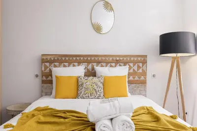 a bedroom with a bed with yellow pillows and a mirror at Good Vibes - 10mn from harbor, 5mn from Palais and train station, central, AC, comfy in Cannes