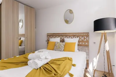 a bedroom with a large bed with yellow pillows at Good Vibes - 10mn from harbor, 5mn from Palais and train station, central, AC, comfy in Cannes