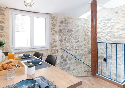 a dining room with a table and a stone wall at NEW Le Backstage Croisette et Plages à 5 min Cannes Lifestyle Central Stay OFFRE SPECIALE in Cannes