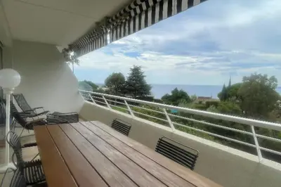 a balcony with a wooden bench and a view of the ocean at Escape in Cannes sea view and shared pool! in Cannes