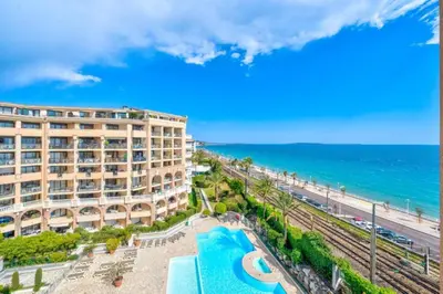 a hotel with a pool and the ocean in the background at La Palme d'Azur - Cannes in Cannes