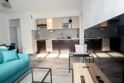 a living room with a blue couch and a kitchen at Charmant 2p proche des plages, appartement Céladon in Cannes