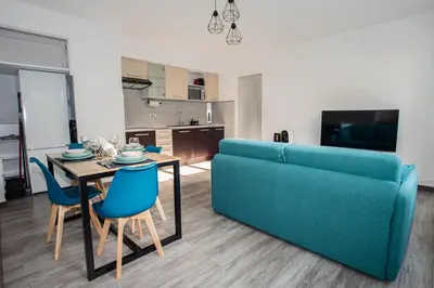 a living room with a blue couch and a table at Charmant 2p proche des plages, appartement Céladon in Cannes
