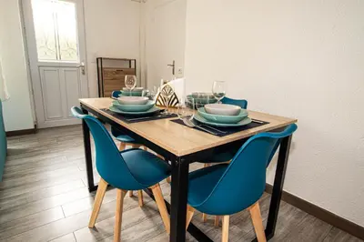 a dining room table with blue chairs and wine glasses at Charmant 2p proche des plages, appartement Céladon in Cannes