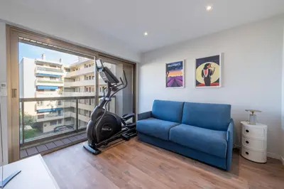 a room with a gym with a blue couch and a treadmill at Beautiful 2-Br Apartment Sea View Beaches Within Walking Distance in Cannes