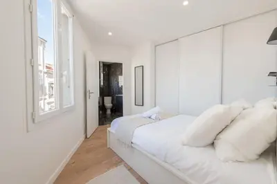 a white bedroom with a large bed with white pillows at Cannes 1-Br Apartment Near the City Center in Cannes