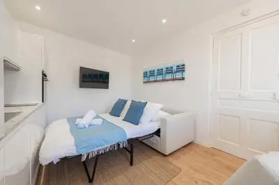 a white room with a bed with blue pillows at Cannes 1-Br Apartment Near the City Center in Cannes