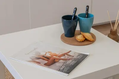 a table with two cups and a magazine on it at Cannes 1-Br Apartment Near the City Center in Cannes