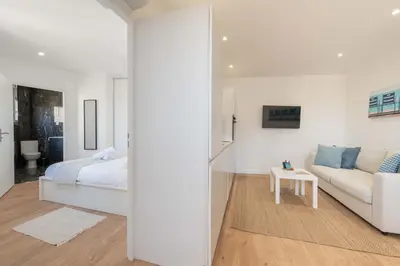 a white bedroom with a bed and a couch at Cannes 1-Br Apartment Near the City Center in Cannes