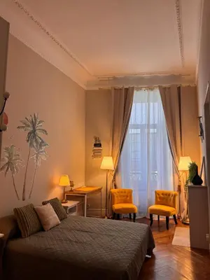 a bedroom with a bed and two orange chairs at Parthenopi suite, le chic de Cannes dans le centre, près du palais in Cannes