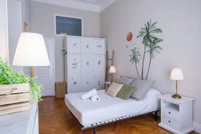 a white bedroom with a bed and a palm tree at Parthenopi suite, le chic de Cannes dans le centre, près du palais in Cannes