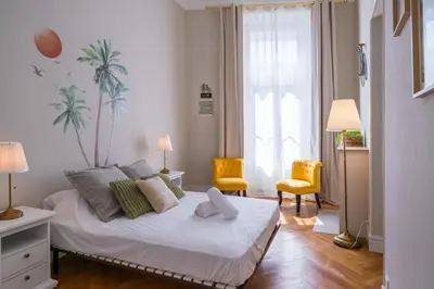 a bedroom with a bed with a palm tree mural on the wall at Parthenopi suite, le chic de Cannes dans le centre, près du palais in Cannes