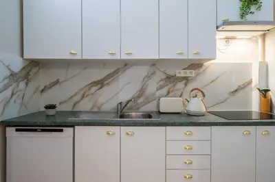 a kitchen with white cabinets and a sink at Parthenopi suite, le chic de Cannes dans le centre, près du palais in Cannes