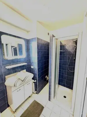 a blue tiled bathroom with a sink and a shower at Le 65 Picaud - Superbe logement proche plages in Cannes