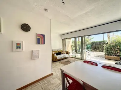 a living room with a table and a clock on a wall at Le 65 Picaud - Superbe logement proche plages in Cannes