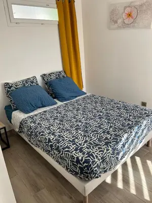 a bed with blue sheets and blue pillows on it at Charming 38m2 city house in Le Cannet