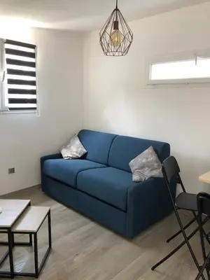 a blue couch in a living room with a table at Charming 38m2 city house in Le Cannet