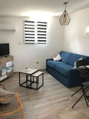 a living room with a blue couch and a table at Charming 38m2 city house in Le Cannet