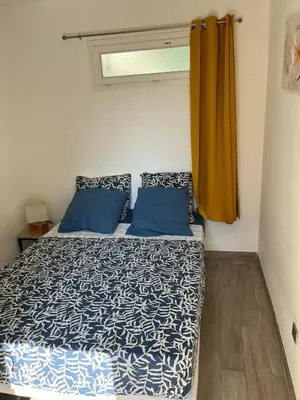 a bedroom with a bed with blue pillows and a window at Charming 38m2 city house in Le Cannet