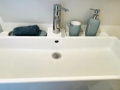 a white sink with two toothbrushes and two cups at Grande studio, Vue mer magnifique in Cannes